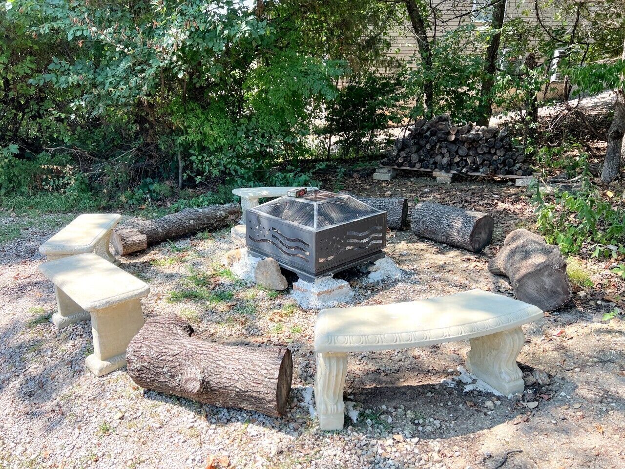 A rustic outdoor seating area with stone benches and a fire pit.