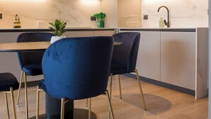 Une cuisine moderne avec un coin repas, comprenant un plan de travail en marbre, des placards intégrés et une chaise noire aux pieds dorés.