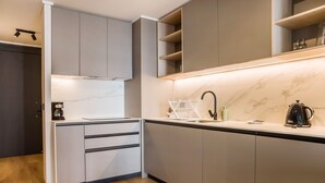 Une cuisine moderne avec des meubles gris, un plan de travail en marbre et un four encastré.