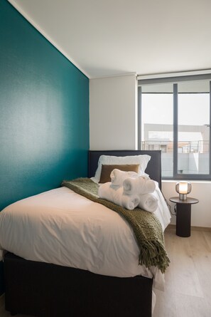 Ein Hotelzimmer mit Bett, Fenster und Nachttisch mit Lampe.