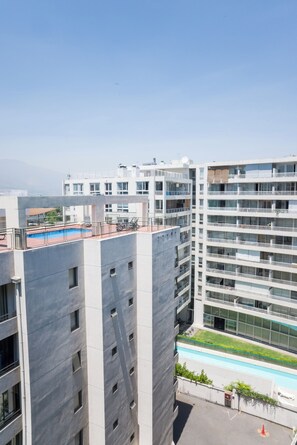 Un immeuble résidentiel à plusieurs étages, doté de balcons, d’une piscine et surplombant un ciel dégagé.