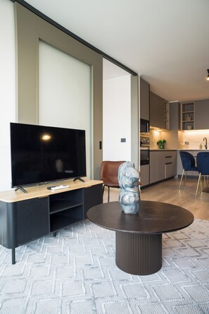 Un salon moderne avec un téléviseur à écran plat, une table basse et une sculpture.
