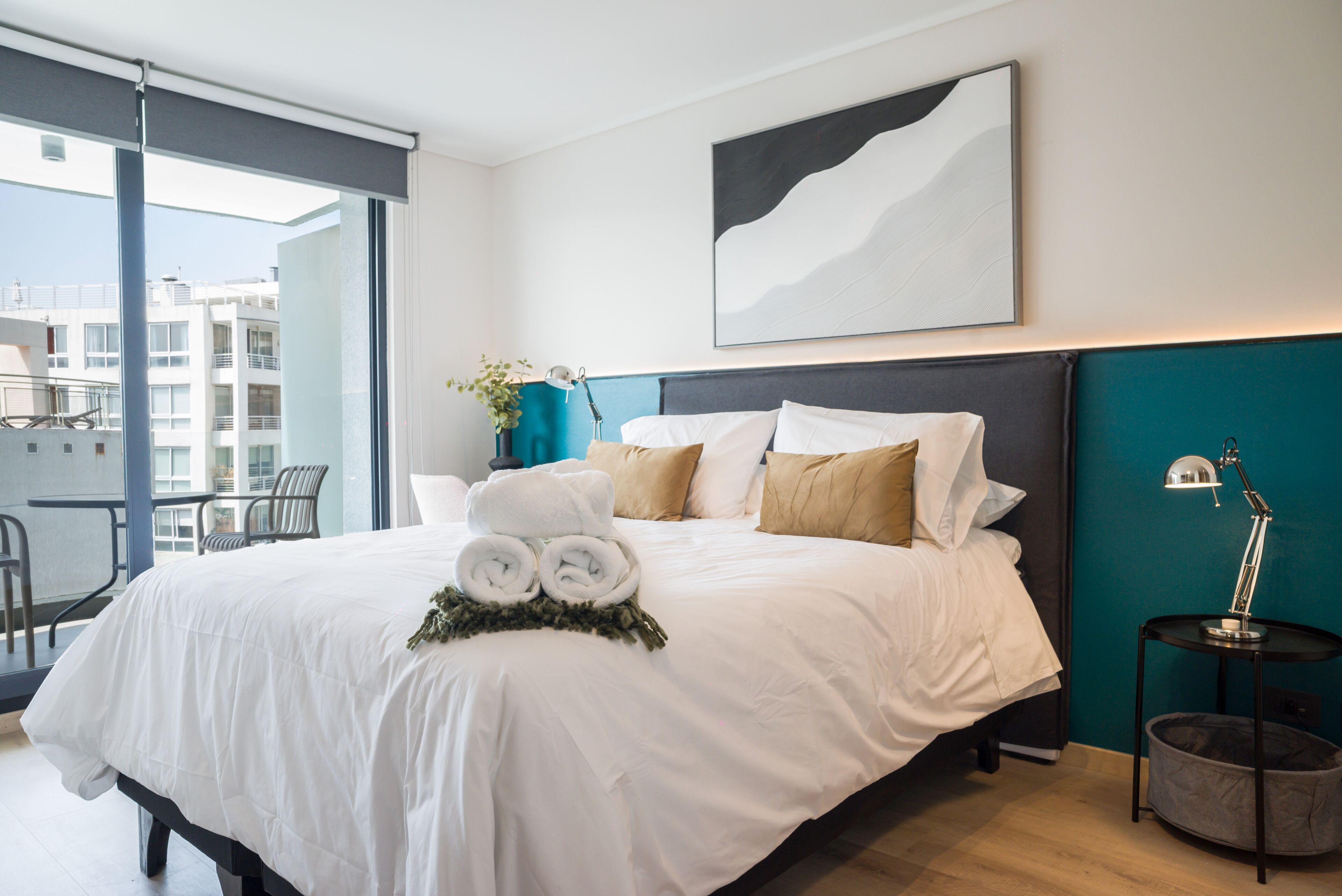 A modern hotel room with a large bed, a view of the city, and a balcony.