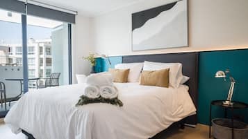 A modern hotel room with a large bed, a view of the city, and a balcony.