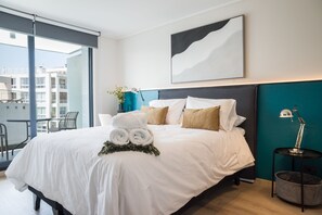 A modern hotel room with a large bed, a view of the city, and a balcony.