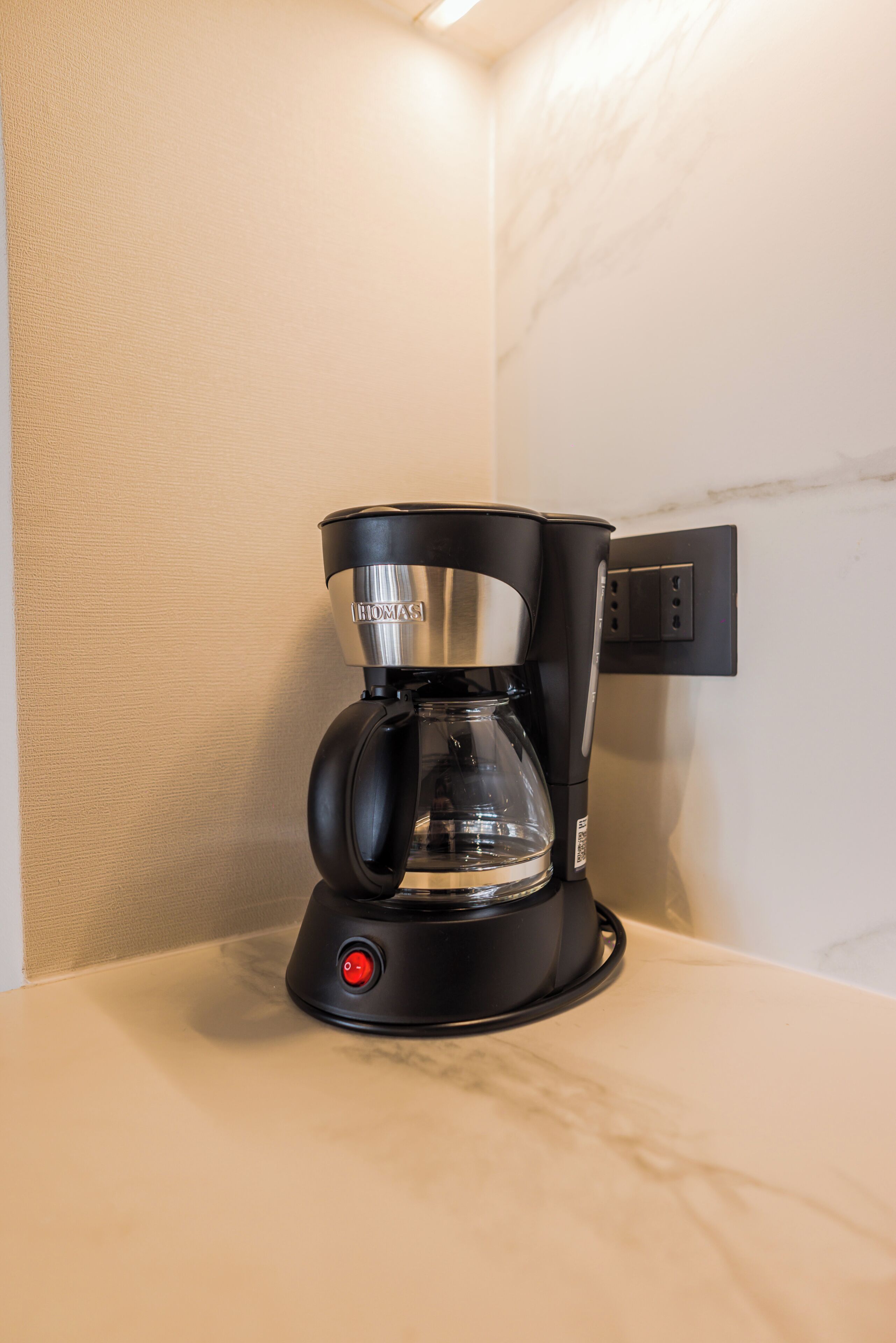 A black coffee maker with a glass carafe on a countertop.