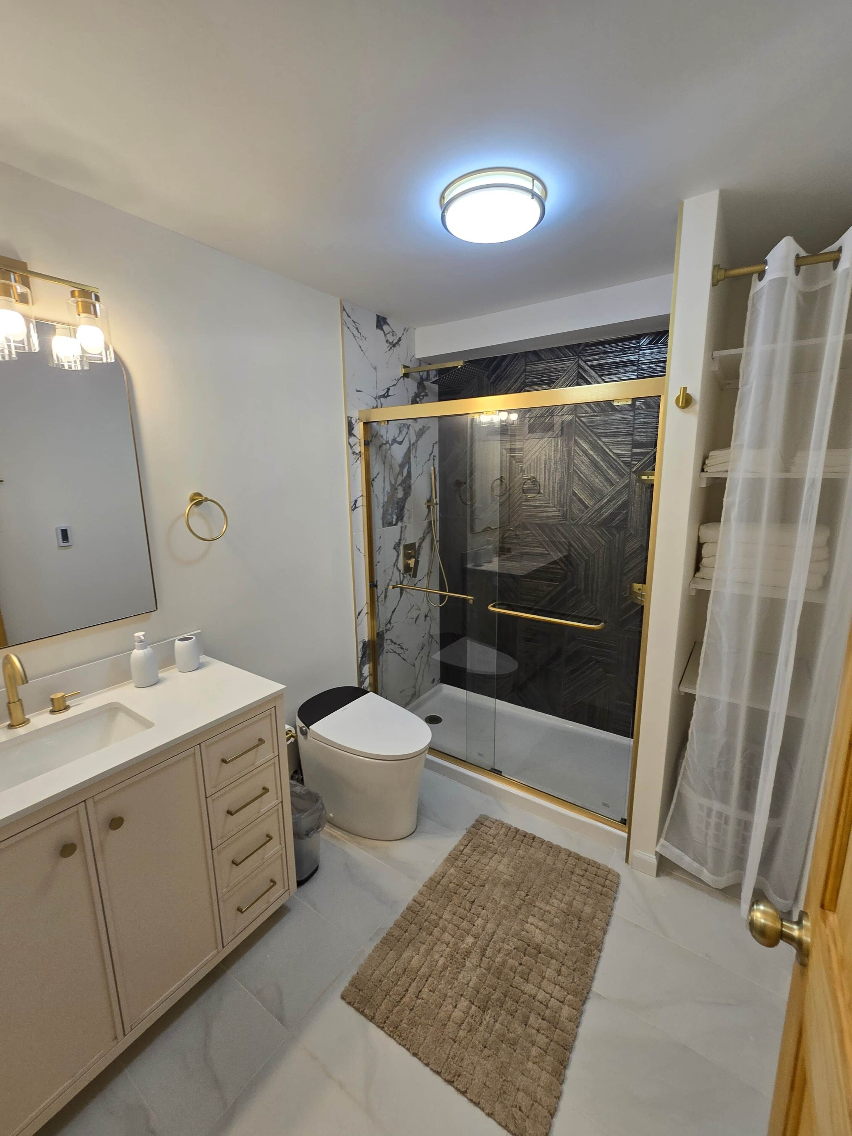 Une salle de bain moderne avec une douche à parois de verre, des toilettes et un meuble-lavabo avec un miroir.