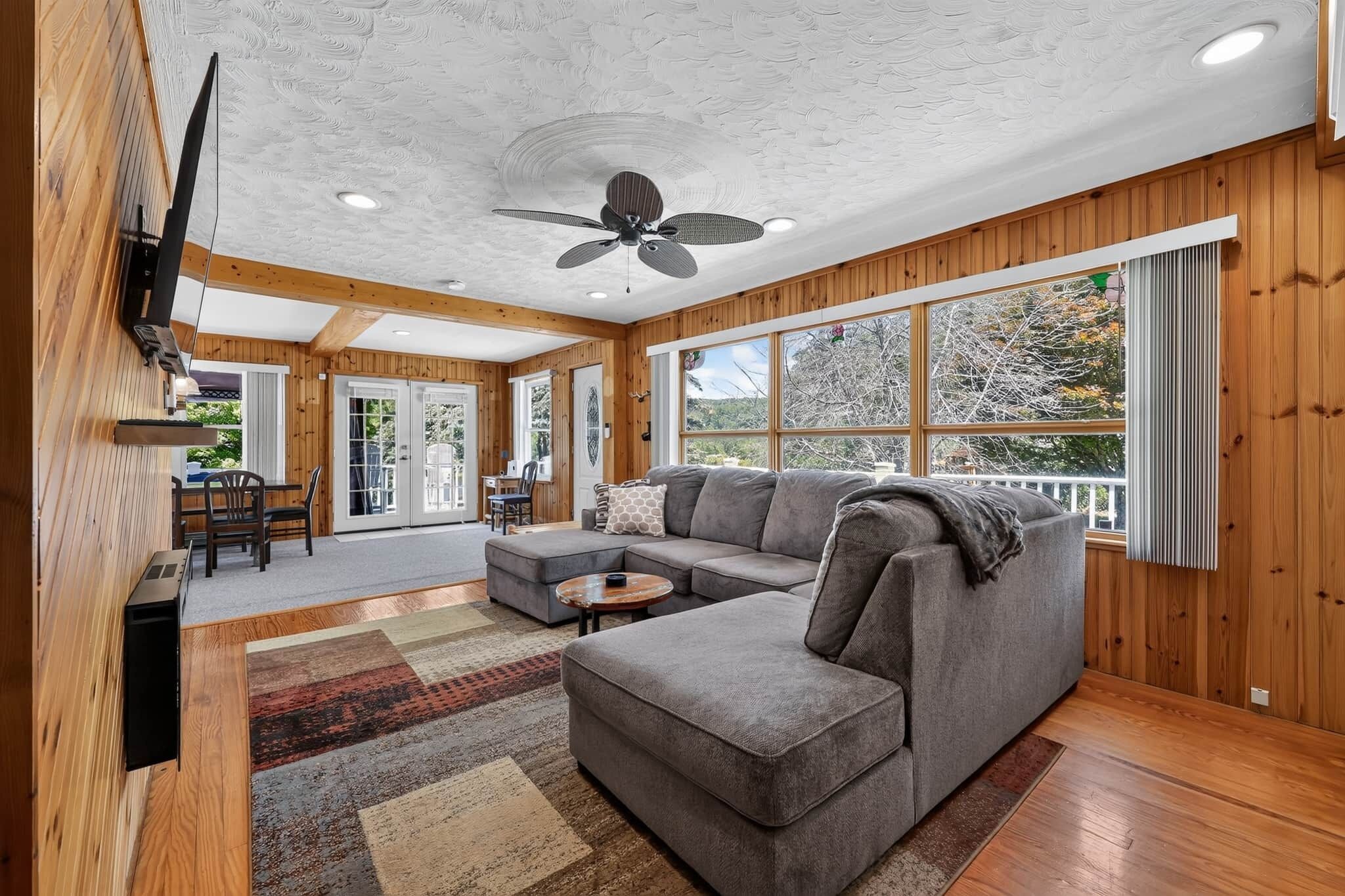 A spacious living room with a sectional sofa, a coffee table, and a ceiling fan.