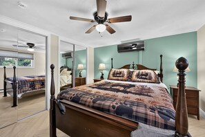 Ein Schlafzimmer mit Bett, Deckenventilator, Spiegel und Fenster.