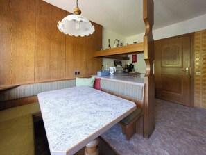 A kitchen with wooden cabinets, a marble countertop, and a hanging light fixture. - Villa zur Gondel (Waidring)