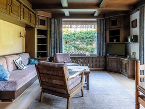 A cozy living room with a sofa, armchair, and a television. - Villa zur Gondel (Waidring)