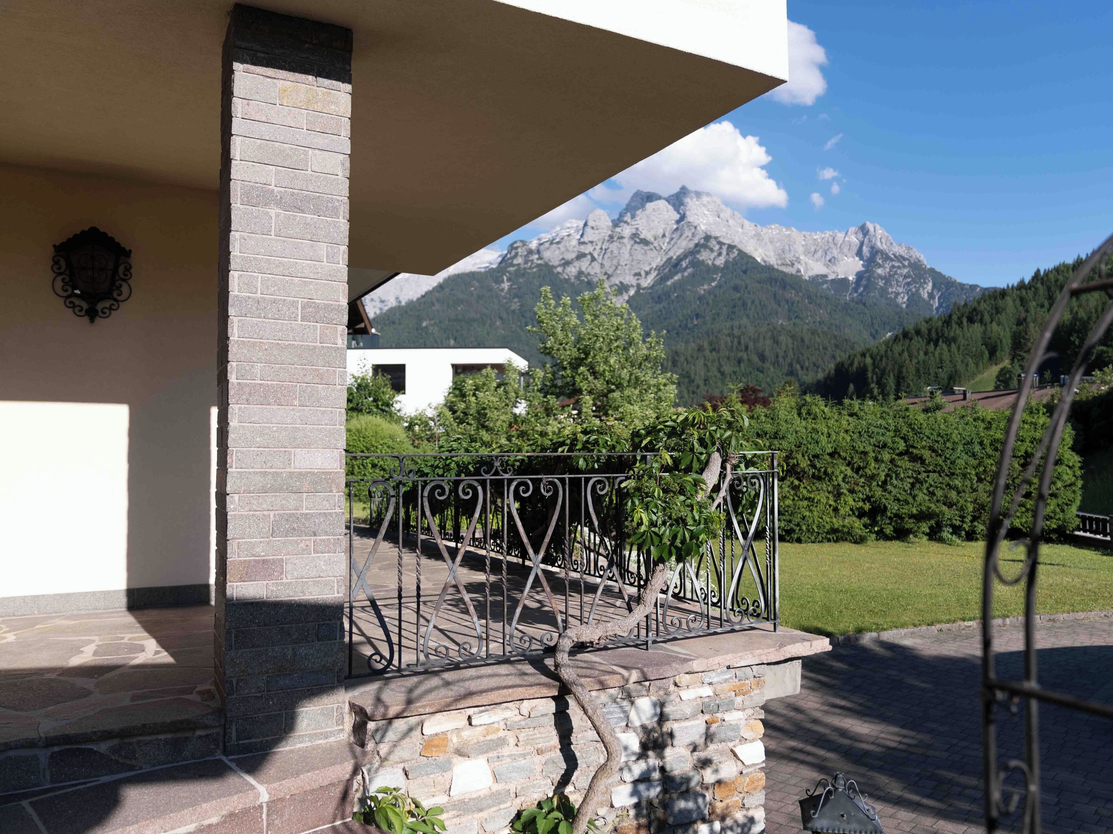 Eine steile Steintreppe führt zu einem Balkon mit Metallgeländer, der auf eine gebirgige Landschaft blickt.