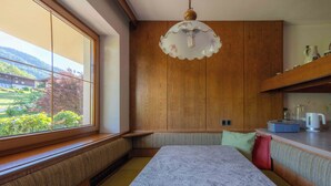 Eine Küche mit Holzschränken, einer Marmorarbeitsplatte, einer integrierten Sitzbank und einem Fenster mit Blick auf Grünflächen.