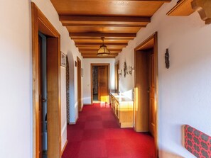 A hallway with wooden doors, a red carpet, and a wooden ceiling. - Villa zur Gondel (Waidring)