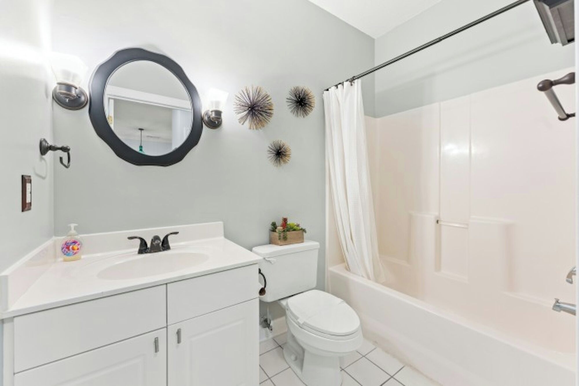 A bathroom with a white sink, toilet, and shower area.