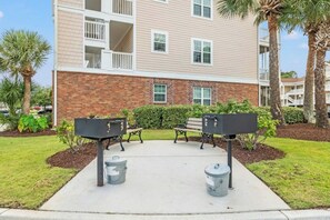 A courtyard with outdoor seating, a trash can, and a mailbox. - Barefoot Cypress 523- 2 Bedroom Condo (North Myrtle Beach)