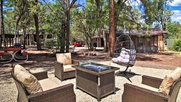 An outdoor seating area with wicker furniture, a glass-top table, and a hanging chair.