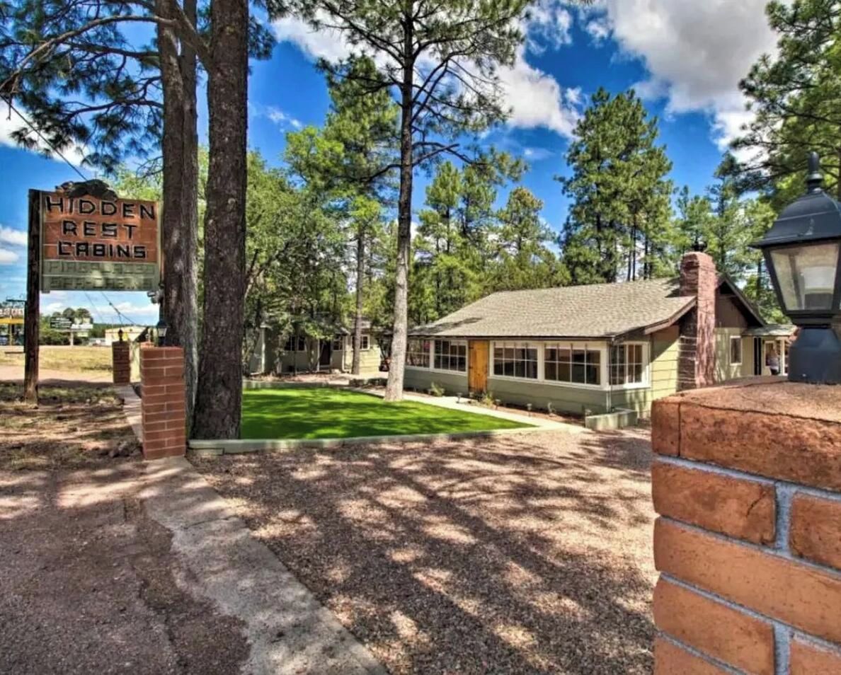 A cabin with a sign indicating 'Hidden Rest Cabins' in a wooded area.