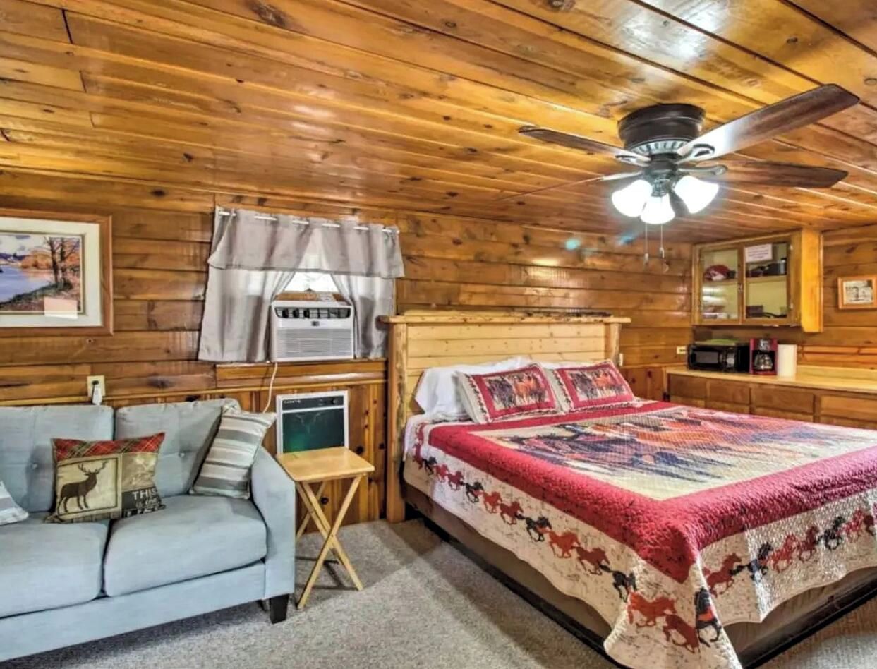 Une pièce confortable avec un lit, un canapé, un ventilateur de plafond et une fenêtre avec des rideaux.