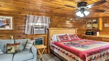 A cozy room with a bed, a sofa, a ceiling fan, and a window with curtains.