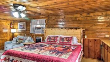 L'intérieur d'une cabane en bois, avec un lit, un canapé et un ventilateur de plafond.