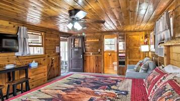 A wooden cabin interior with a bed, a desk, and a couch.