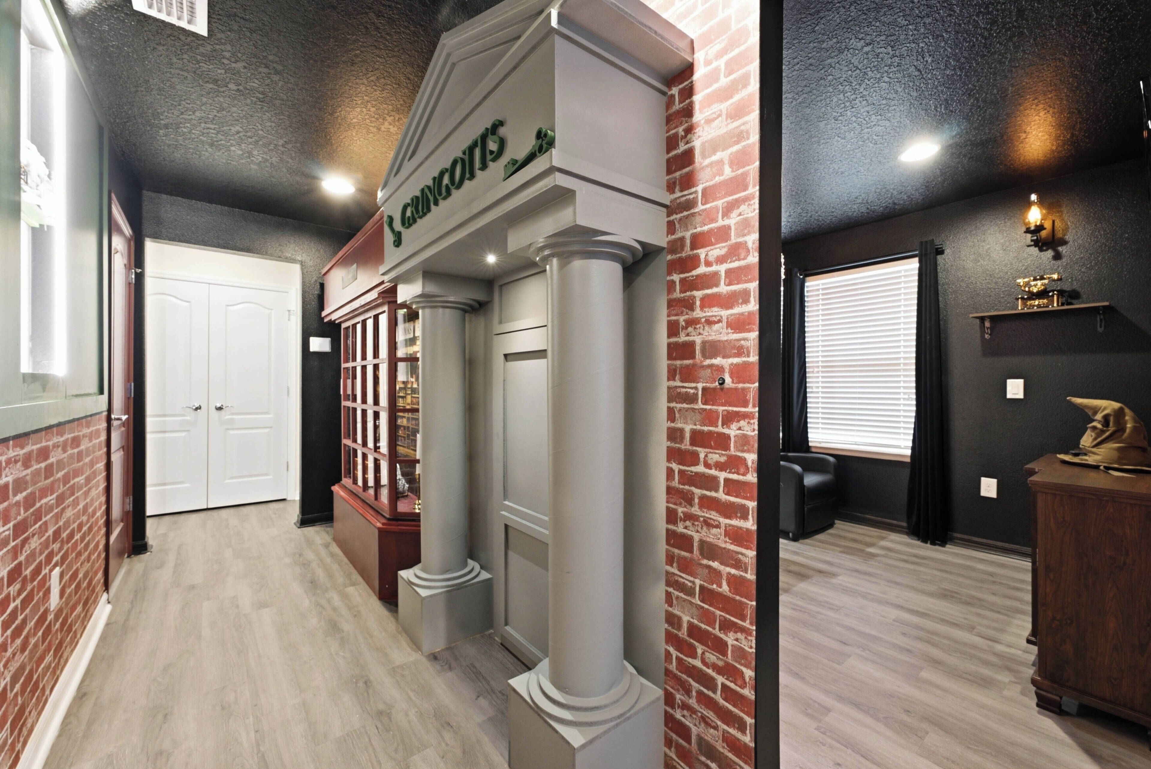 A hallway with a brick wall, a white door, and a sign above a column that reads 'Gongorits'.
