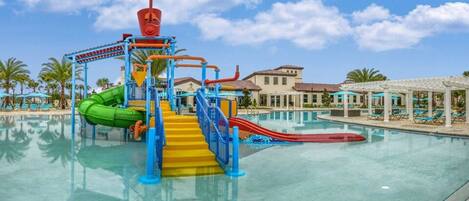 A water park with slides and a pool, surrounded by palm trees and a clear sky.