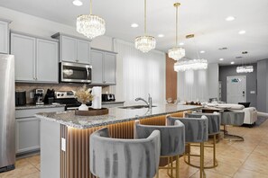 A modern kitchen with a central island, bar stools, stainless steel appliances, and pendant lighting. - Disney Dream Home | Mickey, UP, Harry Potter(2100) (Kissimmee)