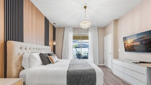 Ein modernes Schlafzimmer mit einem großen Bett, einem Fernseher und Blick ins Freie.