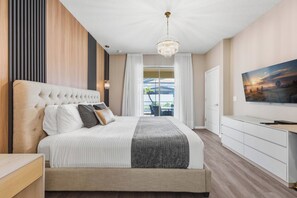 A modern bedroom with a large bed, a television, and a view of the outdoors. - Disney Dream Home | Mickey, UP, Harry Potter(2100) (Kissimmee)
