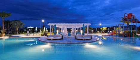 A swimming pool with a covered seating area and a children's play structure.