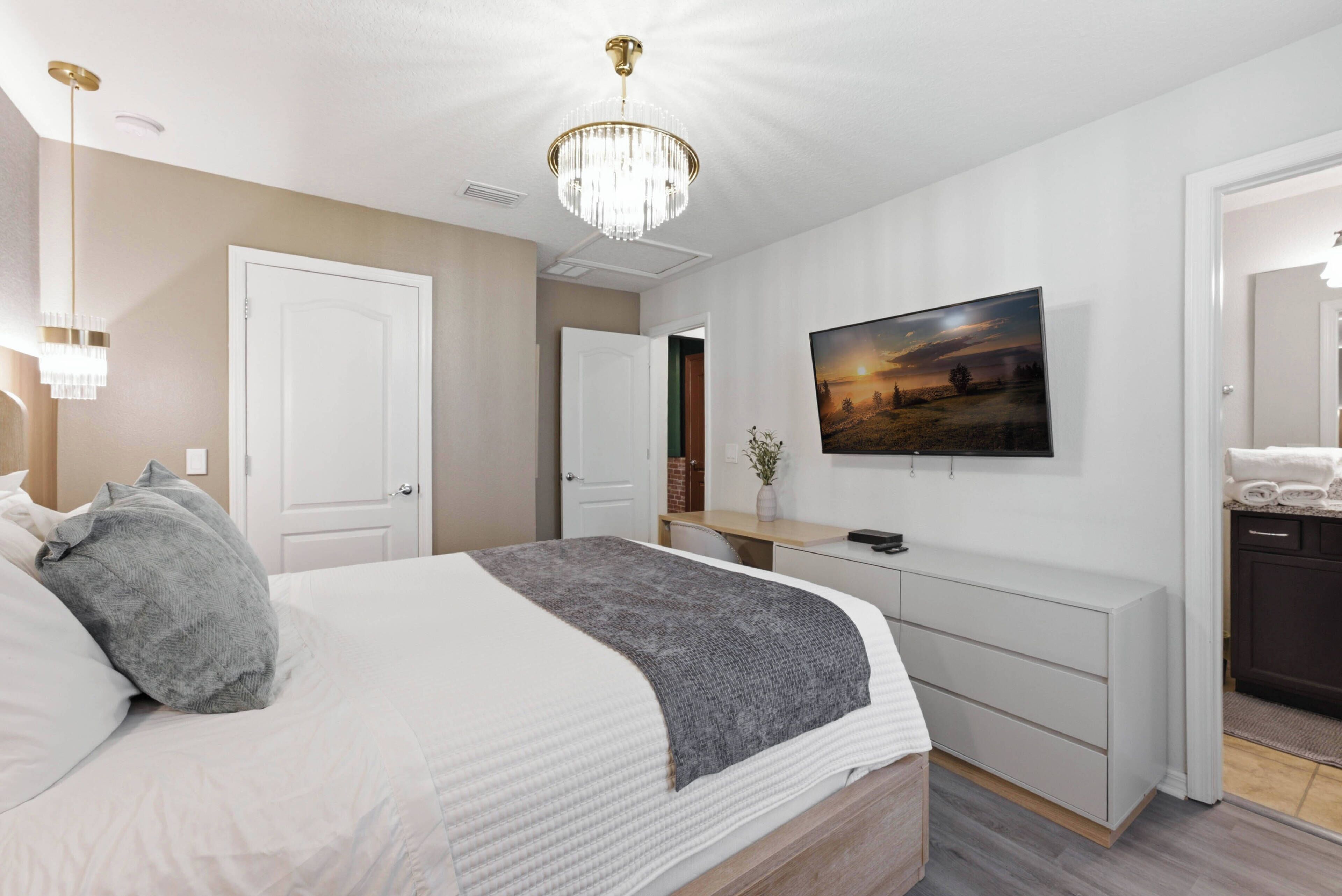 A bedroom with a bed, bedside tables, a TV, and a door.