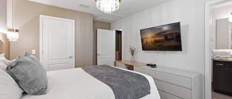 A bedroom with a bed, bedside tables, a TV, and a door.