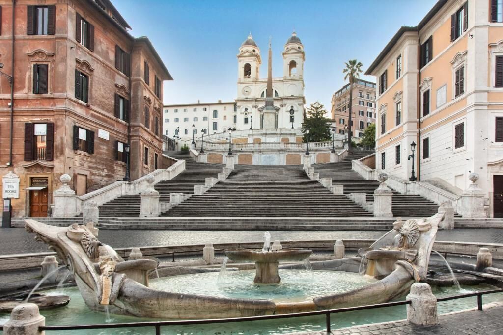 A grand staircase leading to a church with a fountain in the foreground.