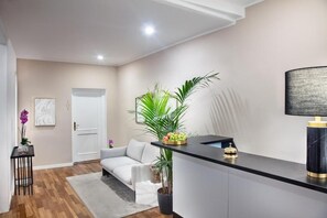 A modern reception area with a black counter, a white sofa, and a potted plant. - Fellini Design Apartment (Roma)
