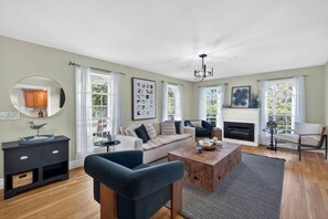 Ein geräumiges Wohnzimmer mit Kamin, einer Couch, einem Couchtisch und einem Essbereich.