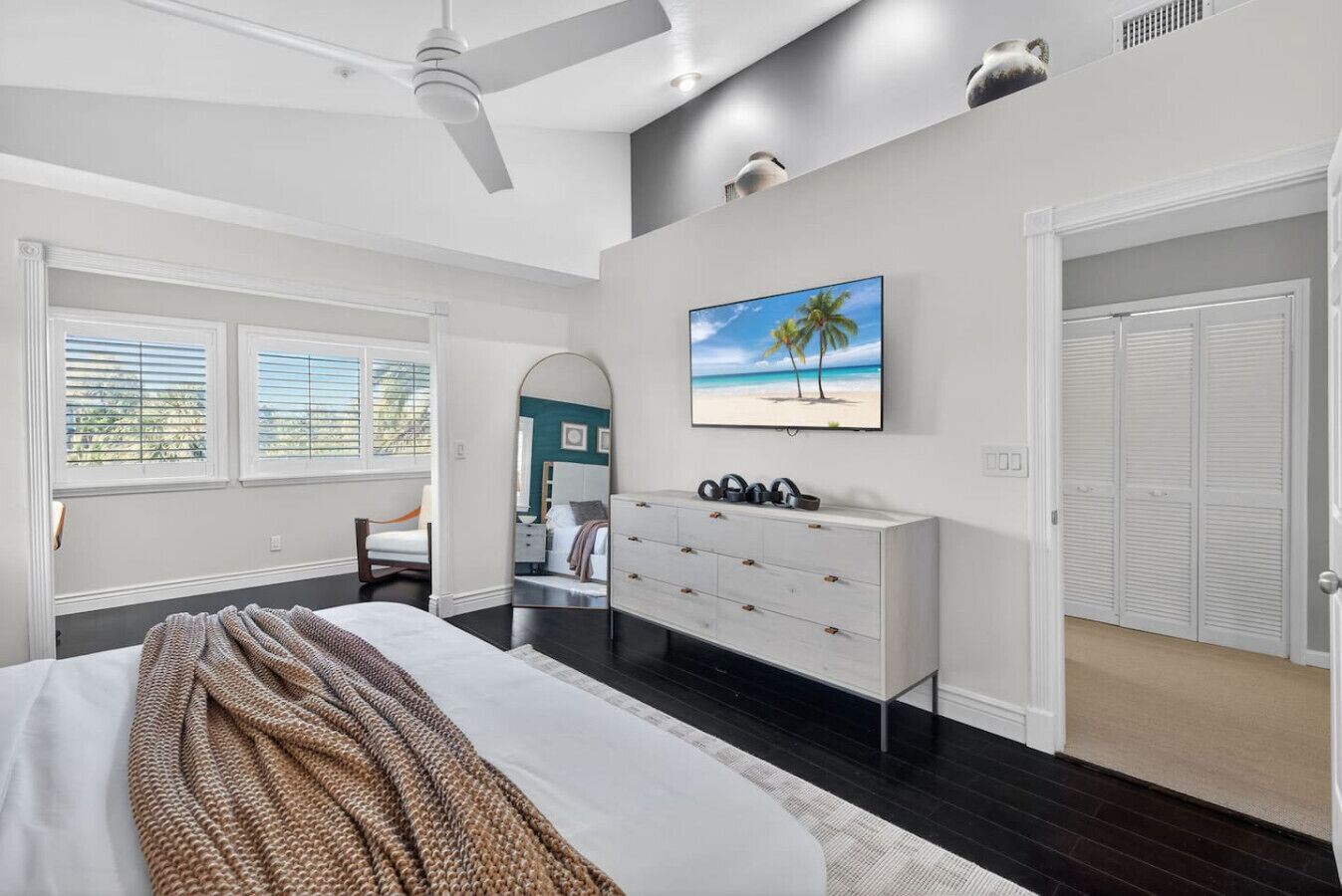 A bedroom with a bed, dresser, TV, and closet.