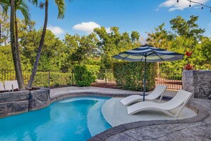Uma piscina com duas espreguiçadeiras e um guarda-sol.