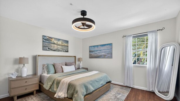 A bedroom with a bed, bedside tables, a ceiling fan, and a window with curtains. - Elite Living | Kayak | Joy Pool | Outdoor Kitchen ! (Fort Myers)
