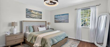 A bedroom with a bed, bedside tables, a ceiling fan, and a window with curtains.