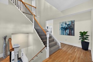 Un escalier avec des rampes en bois et un palier recouvert d’une moquette grise.