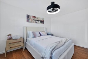 Une chambre à coucher comprenant un lit, des tables de chevet, une commode, une lampe et un luminaire au plafond.