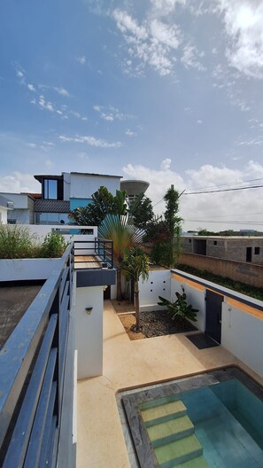 Una terraza en la azotea con piscina, un edificio moderno y un depósito de agua.
