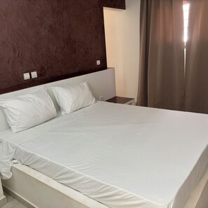 A hotel room with a large bed, a nightstand, and a wall-mounted light switch. - Keur Béryl House - Somone (Somone)