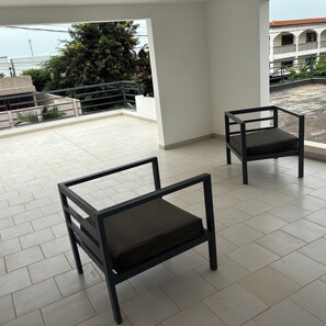 Ein Balkon mit zwei schwarzen Stühlen und einem gefliesten Boden.