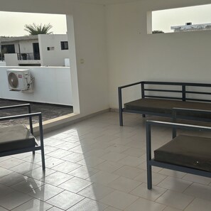 Una terraza en la azotea con zona de estar, un muro blanco y vistas de los edificios circundantes.