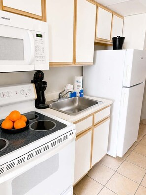 Eine kleine Küche mit Mikrowelle, Herd, Spüle und Kühlschrank.