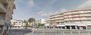 Una zona urbana costera con edificios de varios pisos, palmeras y un paseo peatonal.