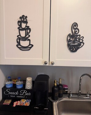 A kitchen with a snack bar area, a coffee maker, and a sink.